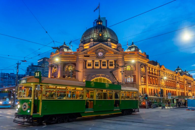 Historic Flinders Street Station with tram at night in Melbourne.