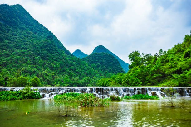 Scenic waterfall with lush mountains in Libo Karst Forest.