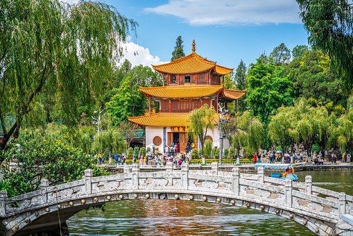 Traditional Chinese pavilion in a garden with a stone bridge.