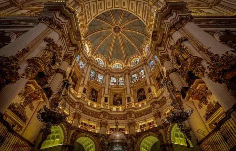 Interior of Seville Cathedral with stained glass and dome.