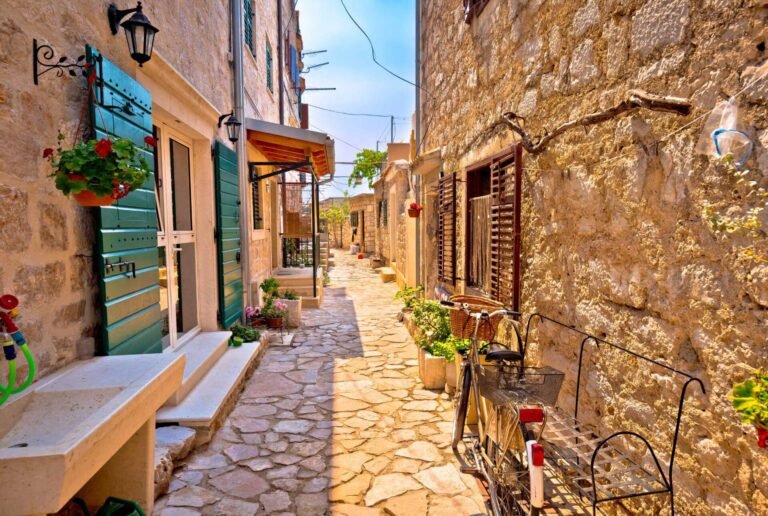 Narrow street in Sibenik with stone buildings and bicycle