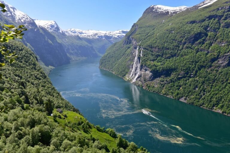 Scenic view of Geiranger Fjord with waterfall and boat