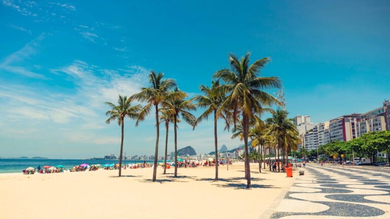 Copacabana Beach with palm trees and cityscape in Rio de Janeiro